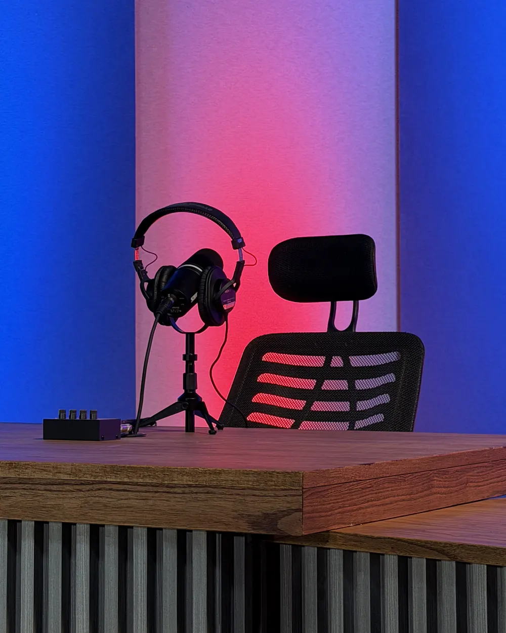 Auriculares Sony sobre un trípode de micrófono, mostrador de madera y paneles de colores en el set de NEXO Studios