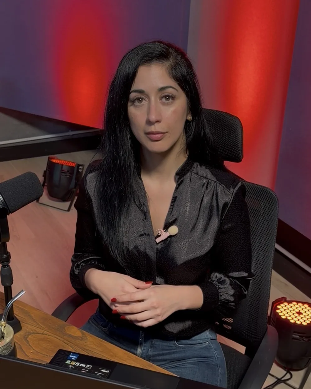Creadora de contenido grabando en la mesa de NEXO Studios con su notebook, micrófono y luz roja de fondo