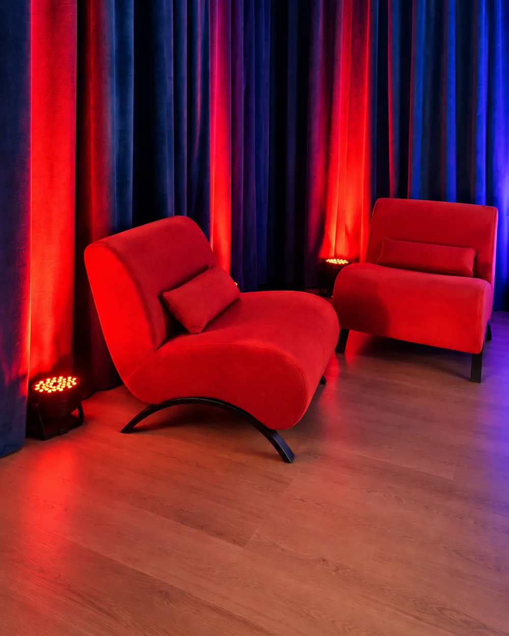 Sillones rojos frente a cortinas de terciopelo azul con luz roja en el rincón de entrevistas de NEXO Studios